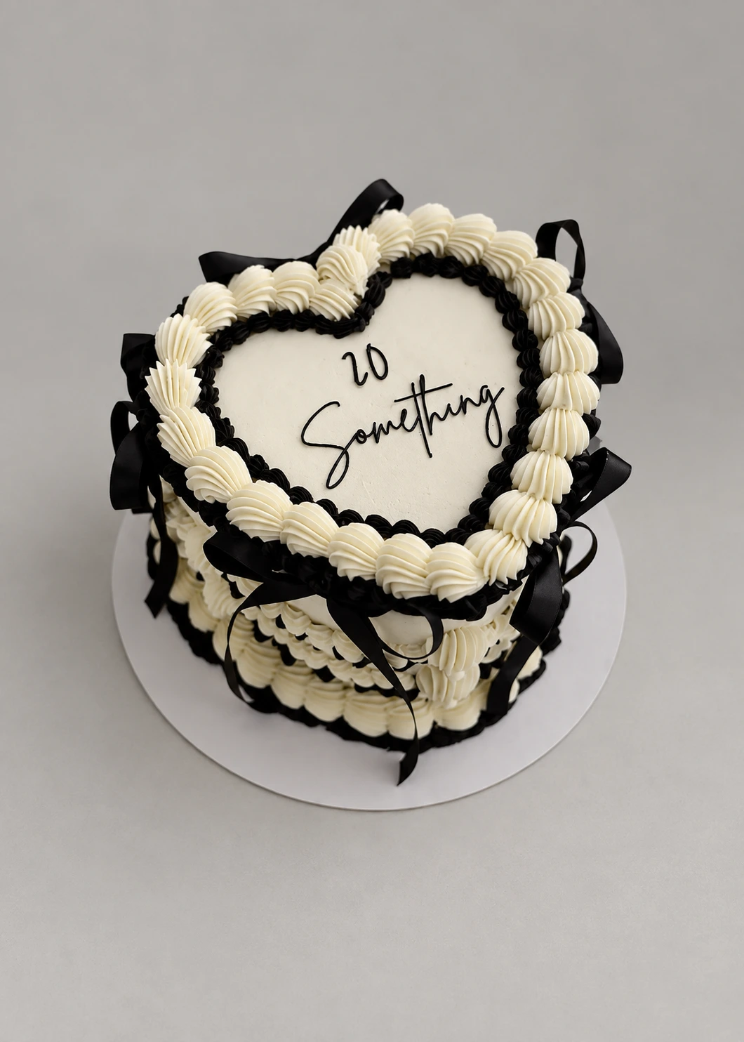 Heart-shaped ivory cake with black ribbon bows, black piping and white shell borders