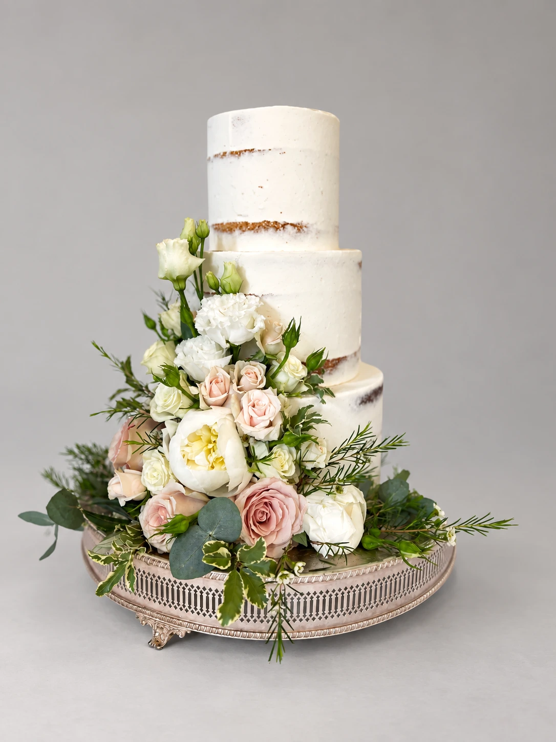 Three-tier semi-naked cake with ivory peonies, blush roses and green foliage