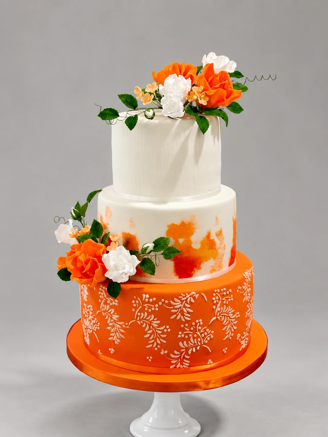 Three-tier ivory and orange cake with orange sugar roses, white blossoms and a stencilled base