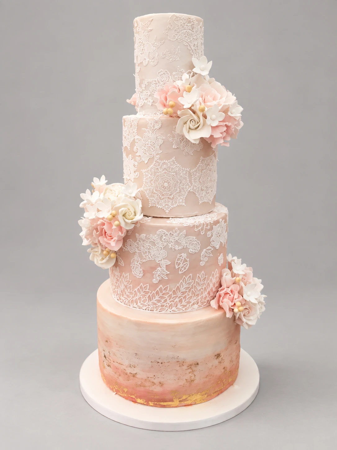Four-tier peach and ivory cake with delicate lace piping and blush sugar flowers
