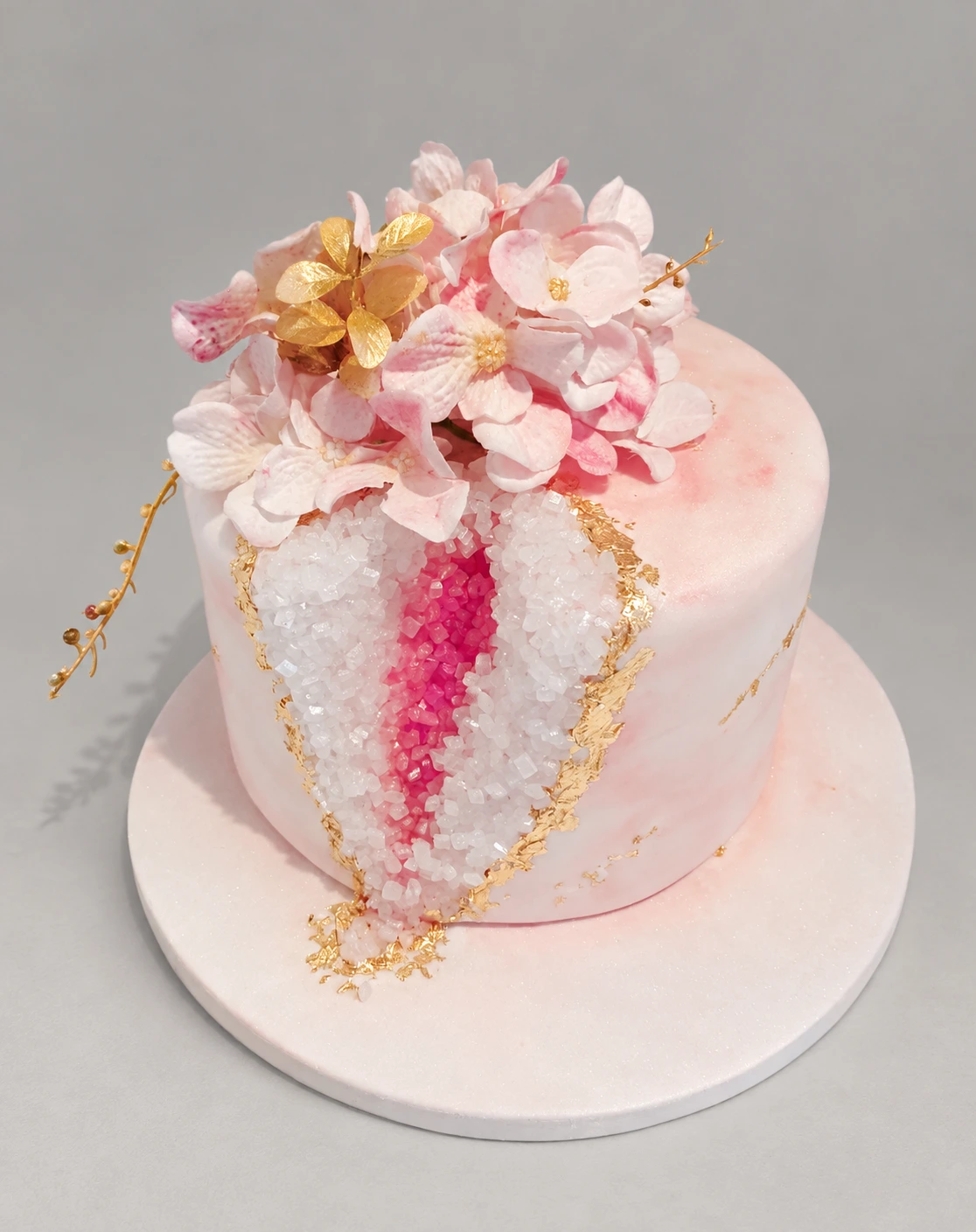 Single-tier pink geode cake with pale blossoms and gold edging