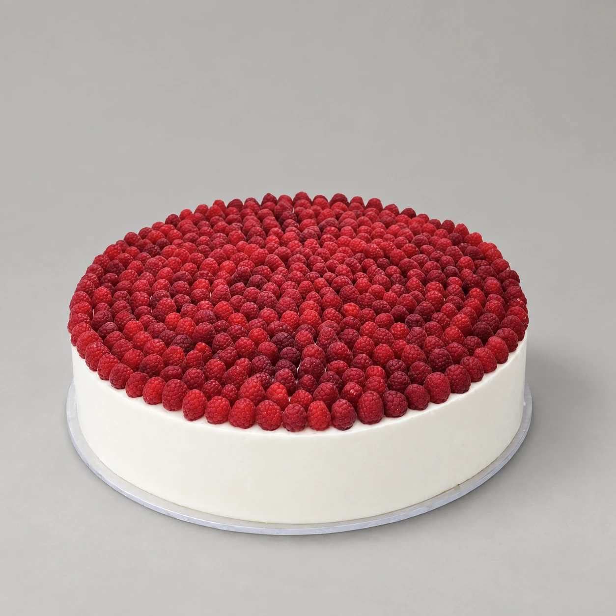 Round white cake covered with red raspberries across the top