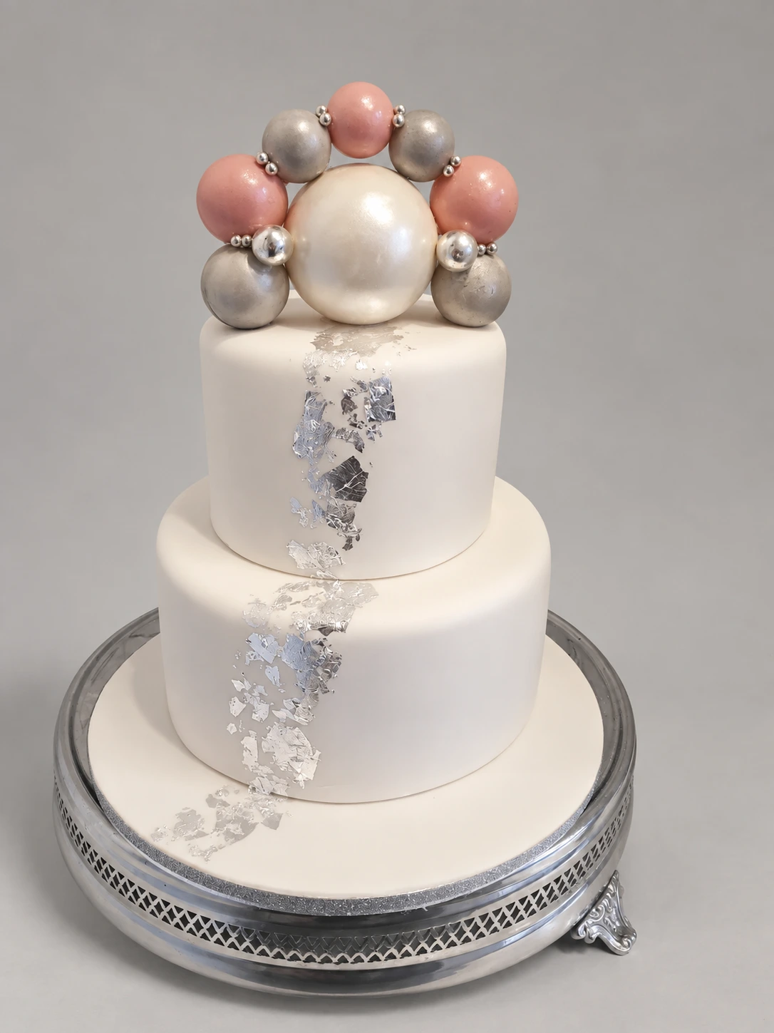 Two-tier white cake with silver leaf and large blush, silver and pearl-like spheres