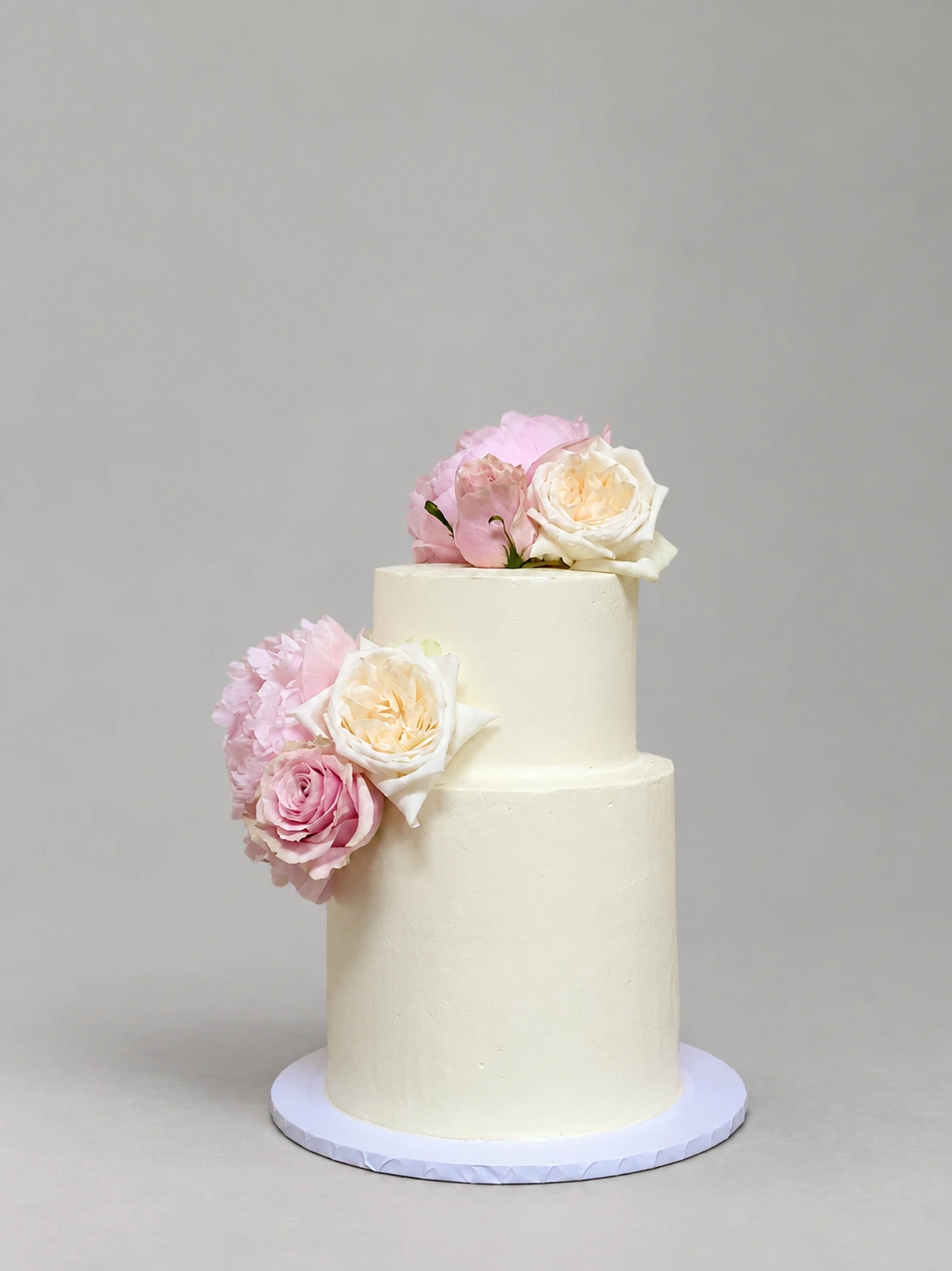 Two-tier ivory wedding cake with blush and ivory roses