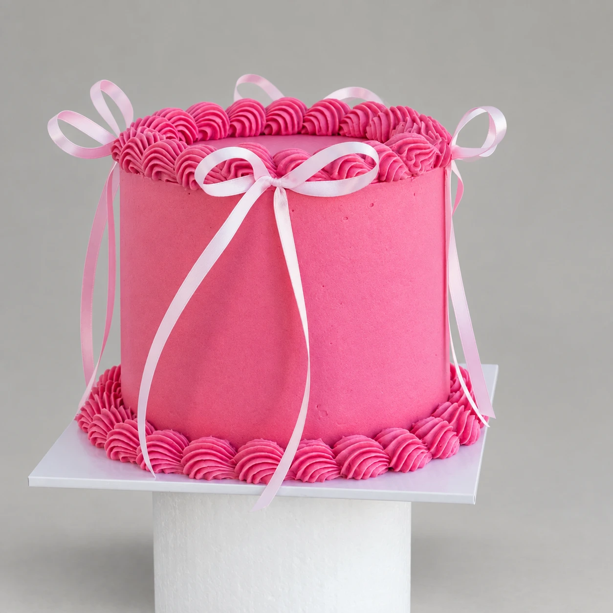 Pink cake with white ribbon bows and pink piped borders