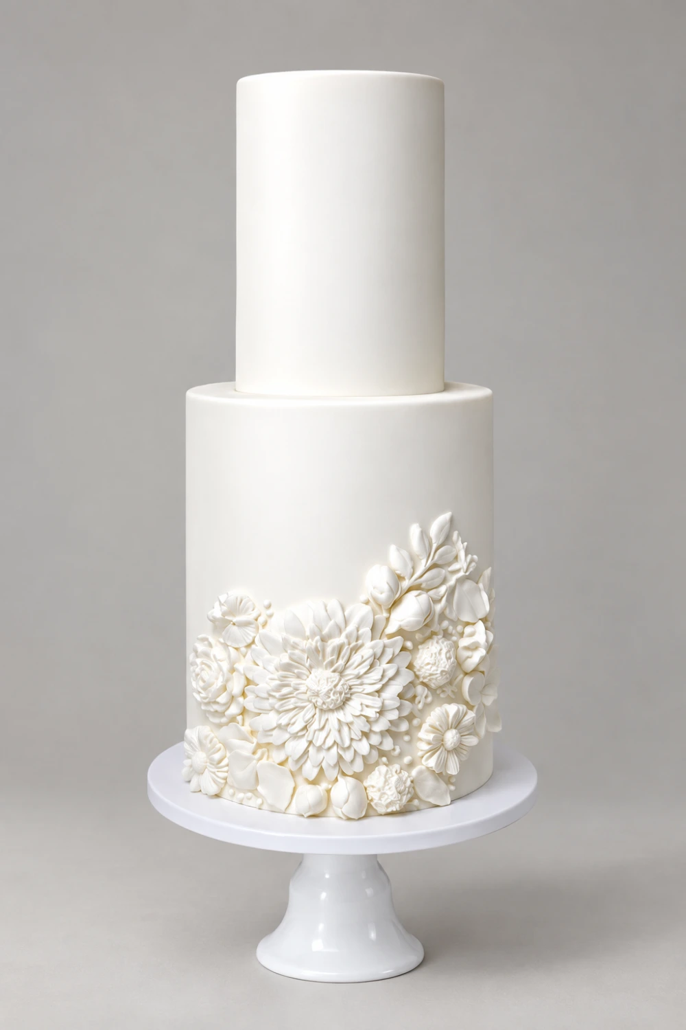 Two-tier white cake with raised white sugar flowers across the lower tier