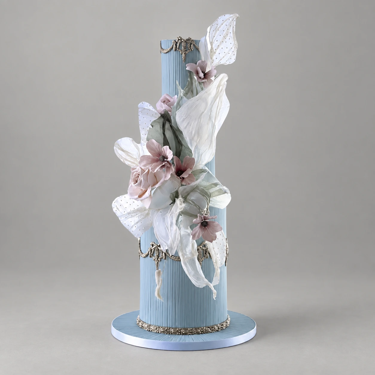 Two extra-tall blue fluted cake tiers with silver filigree, pale sculptural sails and blush flowers