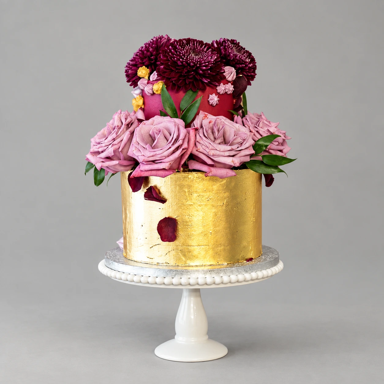 Two-tier gold and burgundy cake with abundant mauve roses and deep burgundy chrysanthemums