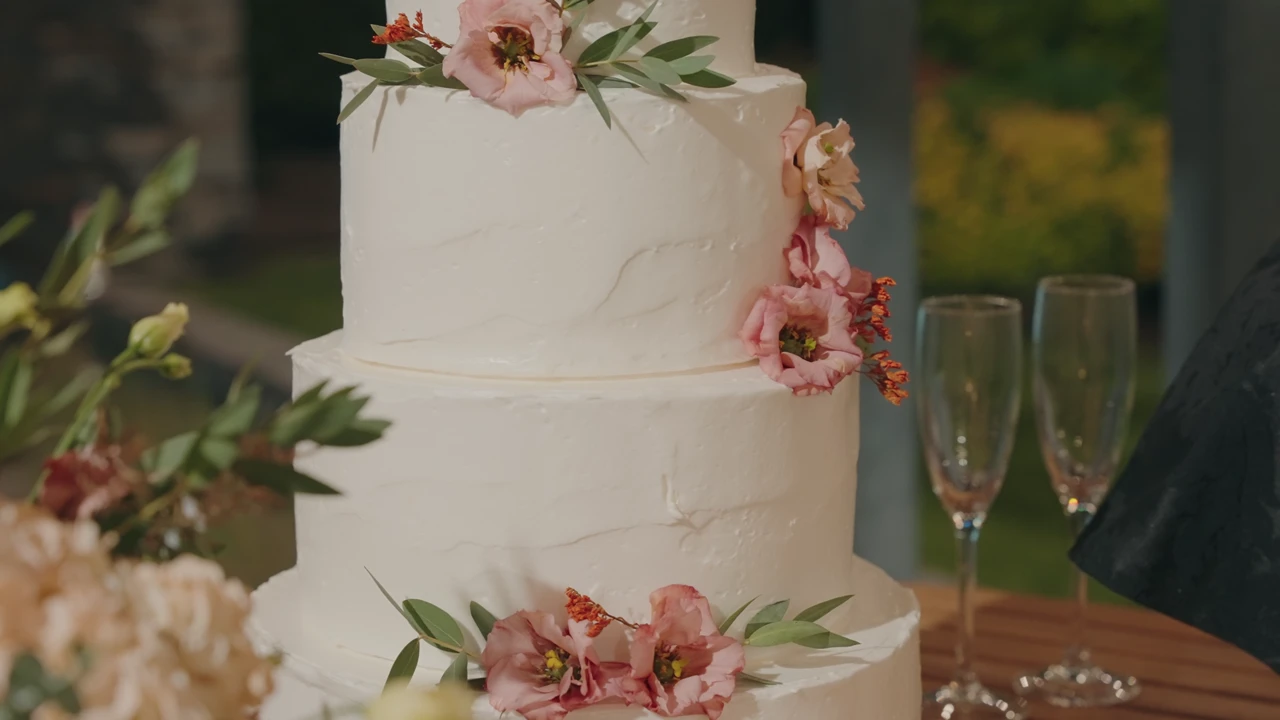 White wedding cake decorated with blush flowers and green foliage